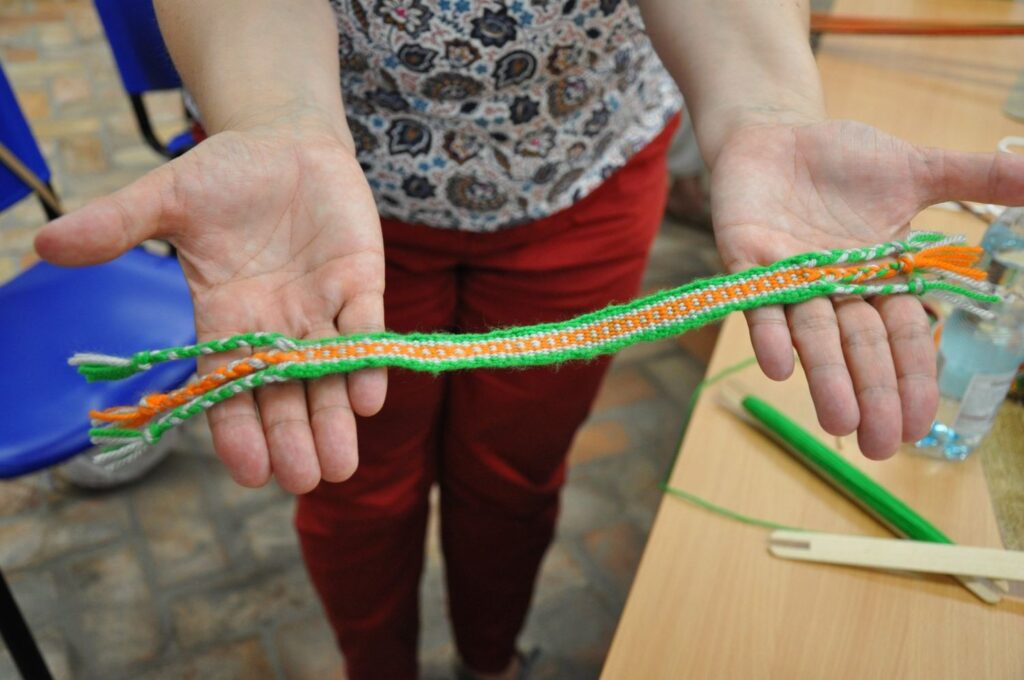 Dłonie prezentujące gotowy, kolorowy produkt wykonany na warsztatach tkackich (kliknięcie powiększy zdjęcie).