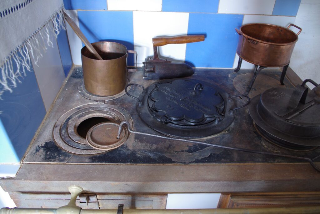 Zabytkowy kuchenny piec z żeliwną płytą grzewczą, garnkami i rondlami używanymi w tradycyjnym gospodarstwie (kliknięcie powiększy zdjęcie).