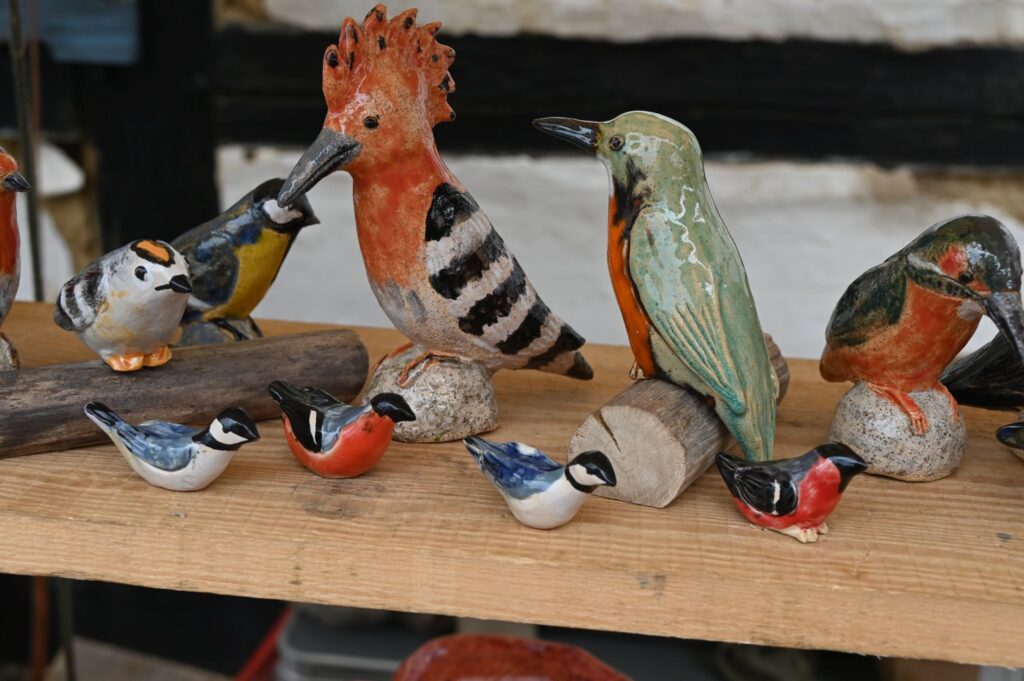 Ceramiczne figurki ptaków i dzięcioła wyeksponowane na półce stoiska rzemieślniczego (kliknięcie powiększy zdjęcie).