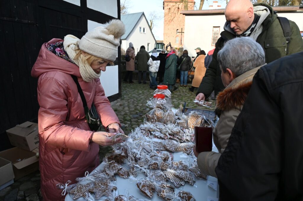Uczestnicy jarmarku wybierają i kupują pierniki oraz wypieki na stoisku z tradycyjnymi słodyczami (kliknięcie powiększy zdjęcie).