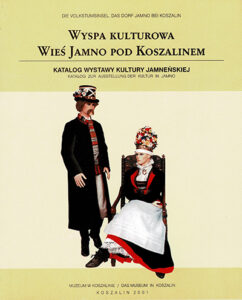 Okładka katalogu wystawy „Wyspa kulturowa. Wieś Jamno pod Koszalinem”. Na jasnym tle widoczna stylizowana scena z dwiema postaciami w tradycyjnych jamneńskich strojach ludowych: stojącym mężczyzną i siedzącą kobietą w bogato zdobionym nakryciu głowy. Publikacja Muzeum w Koszalinie, 2001.